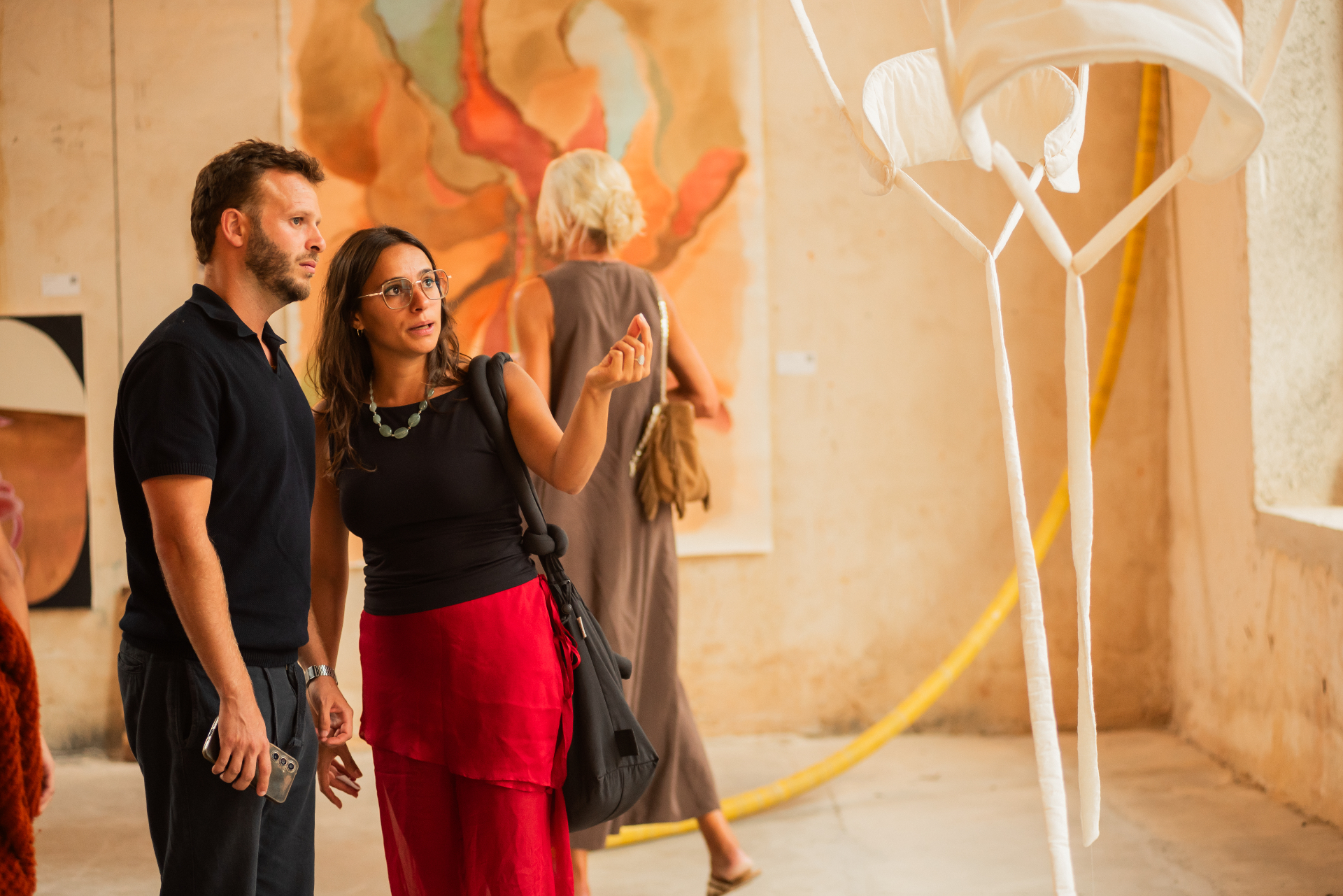 Volume V visitors viewing a watercolour piece beside a hanging fabric sculpture